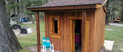 A small wooden cabin with a porch, a window, and a door.