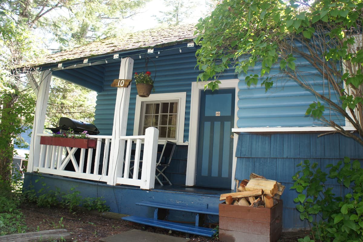 Una casa azul de madera con un porche, una ventana y una puerta.
