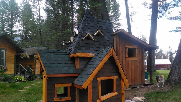 A wooden cabin with a steeply pitched roof, a small porch, and a wooden deck. - Fairmont Mountain Bungalows (Fairmont Hot Springs)