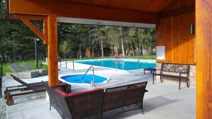 A covered outdoor area with a swimming pool, lounge chairs, and a hot tub. - Fairmont Mountain Bungalows (Fairmont Hot Springs)