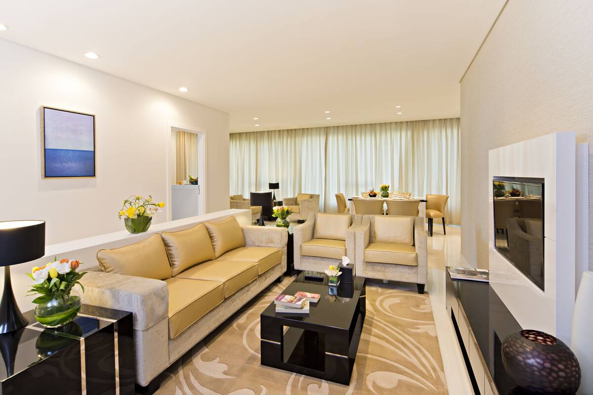 Un salon moderne avec un canapé, une table basse et un téléviseur. Il y a également un coin repas avec une table et des chaises.