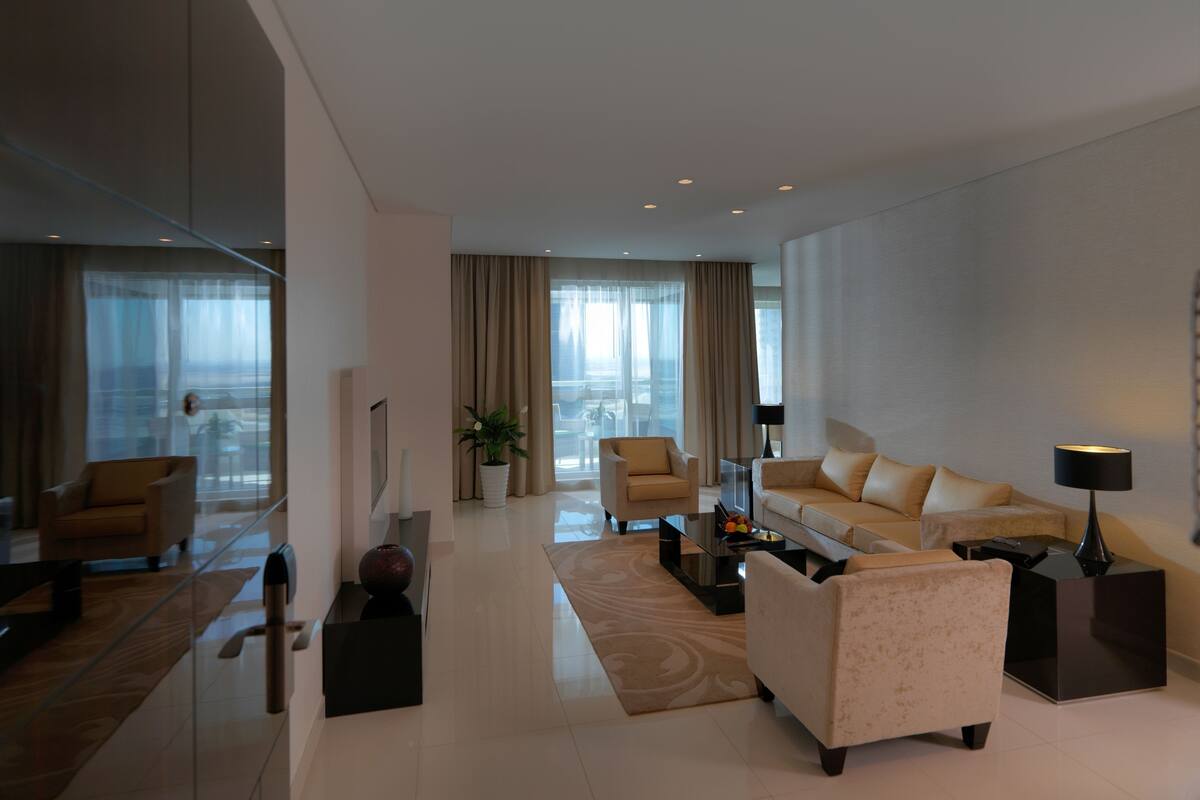 Un salon moderne comprenant un canapé, des fauteuils, une table basse et une table d’appoint avec une lampe.