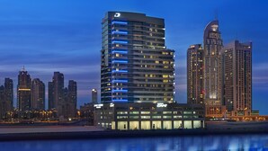 Un hôtel de grande hauteur, avec de nombreux étages, un logo distinctif en forme de « D » et un design moderne.