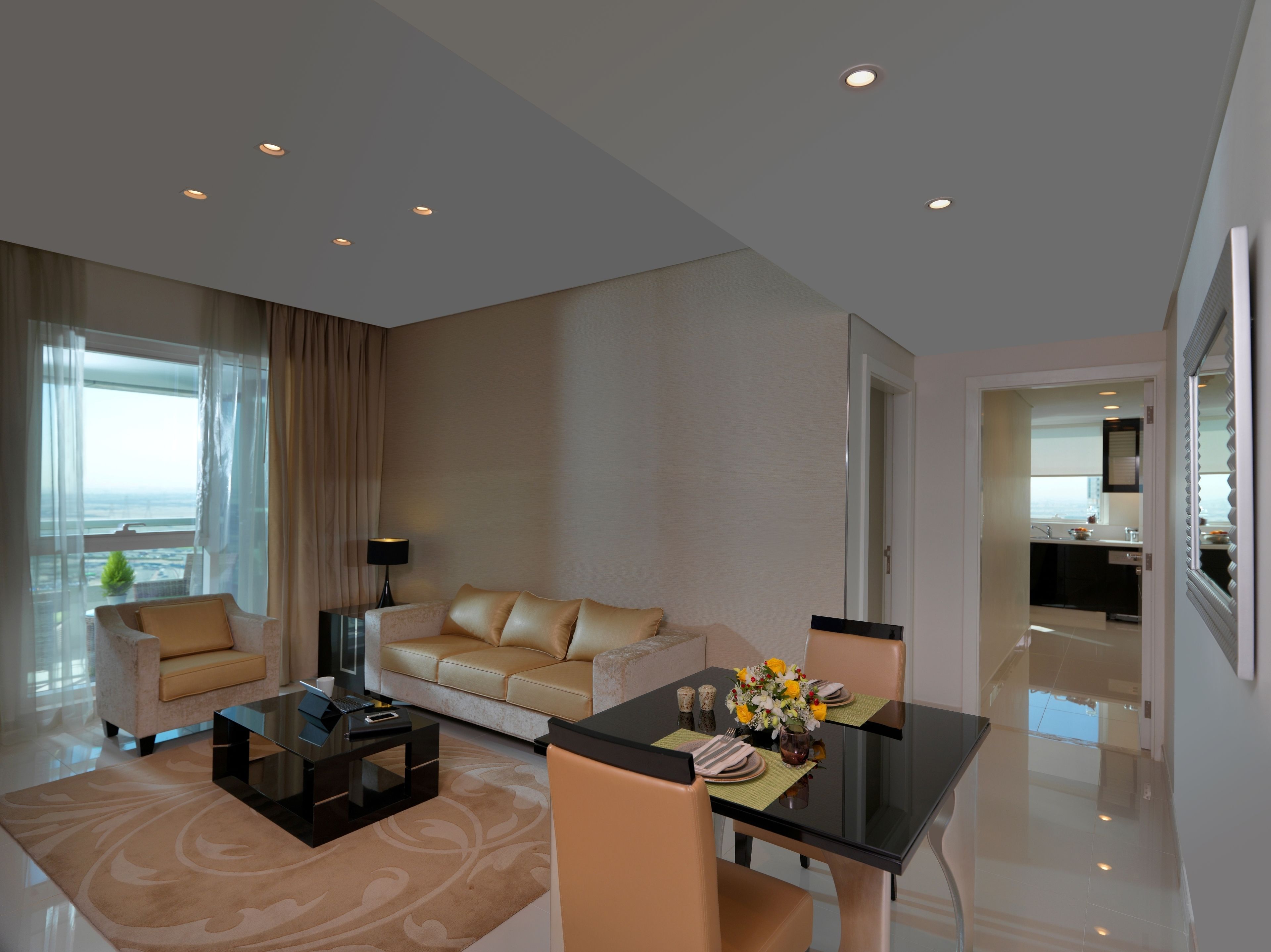 A modern hotel room with a living area, dining table, sofa, and a view of the ocean.