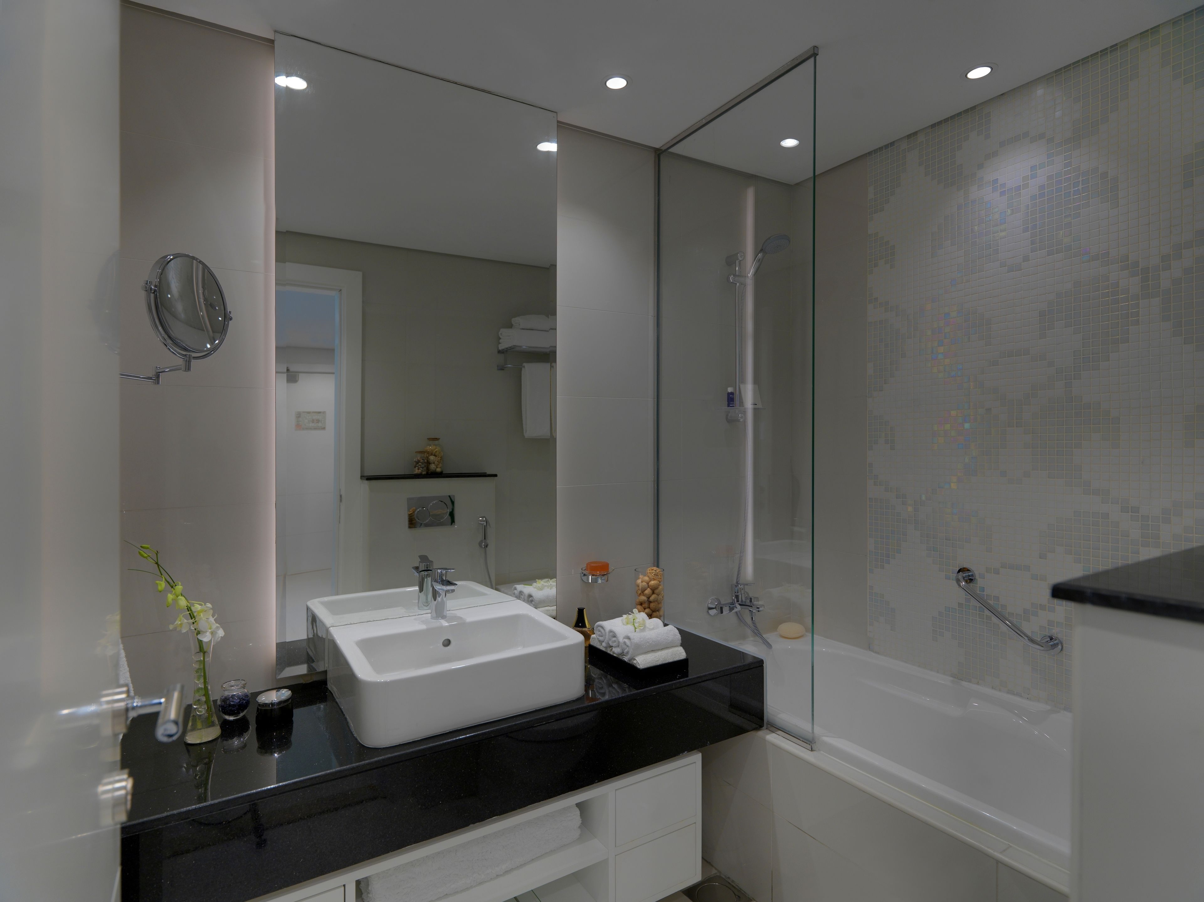 Une salle de bain moderne dotée d’un grand miroir, de deux vasques, d’une baignoire et d’une cabine de douche en verre.