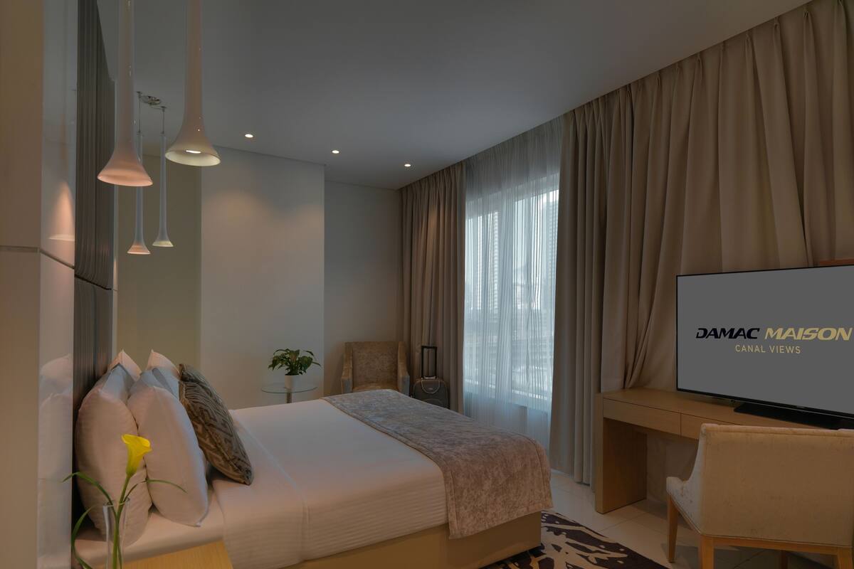 Une chambre d’hôtel moderne équipée d’un lit, d’un bureau, d’une télévision et offrant une vue sur l’extérieur.