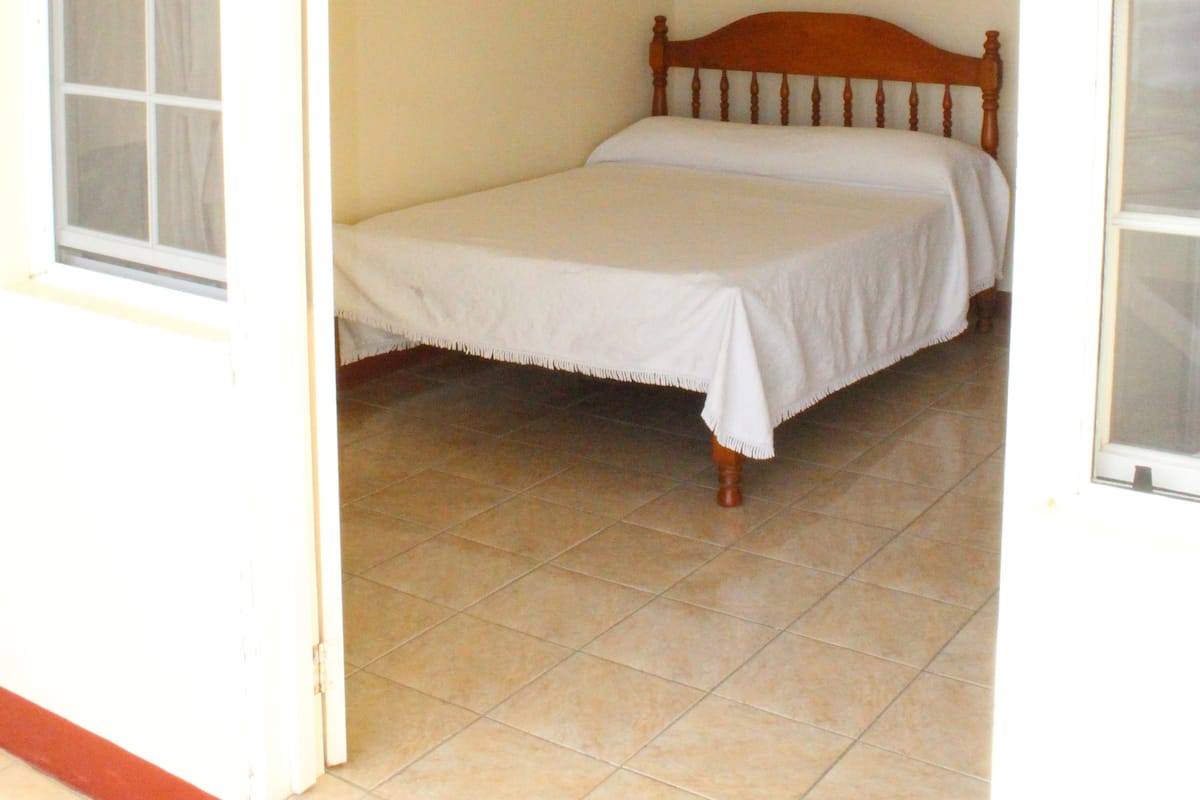 A room with a bed, a window, and a door.