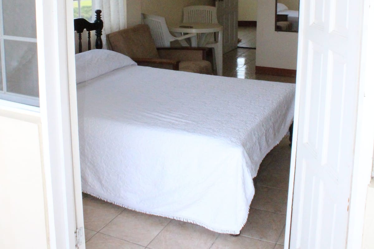 A bedroom with a bed, a chair, and a desk.