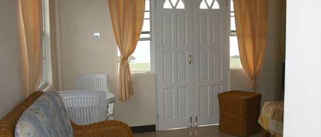 A room with a wicker sofa, a small table, and a white door with windows.