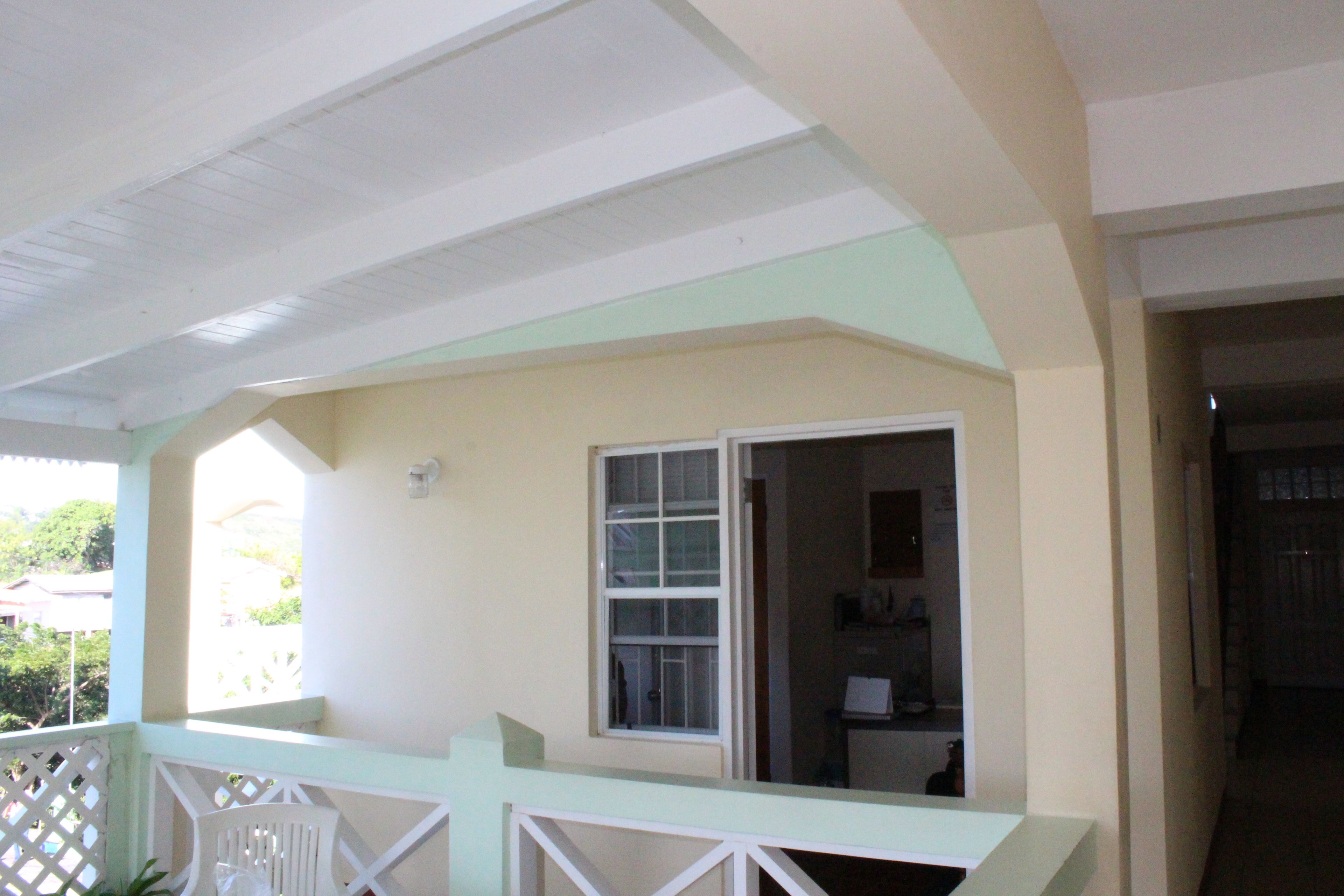A room with a balcony, a window, and a door leading to another room.