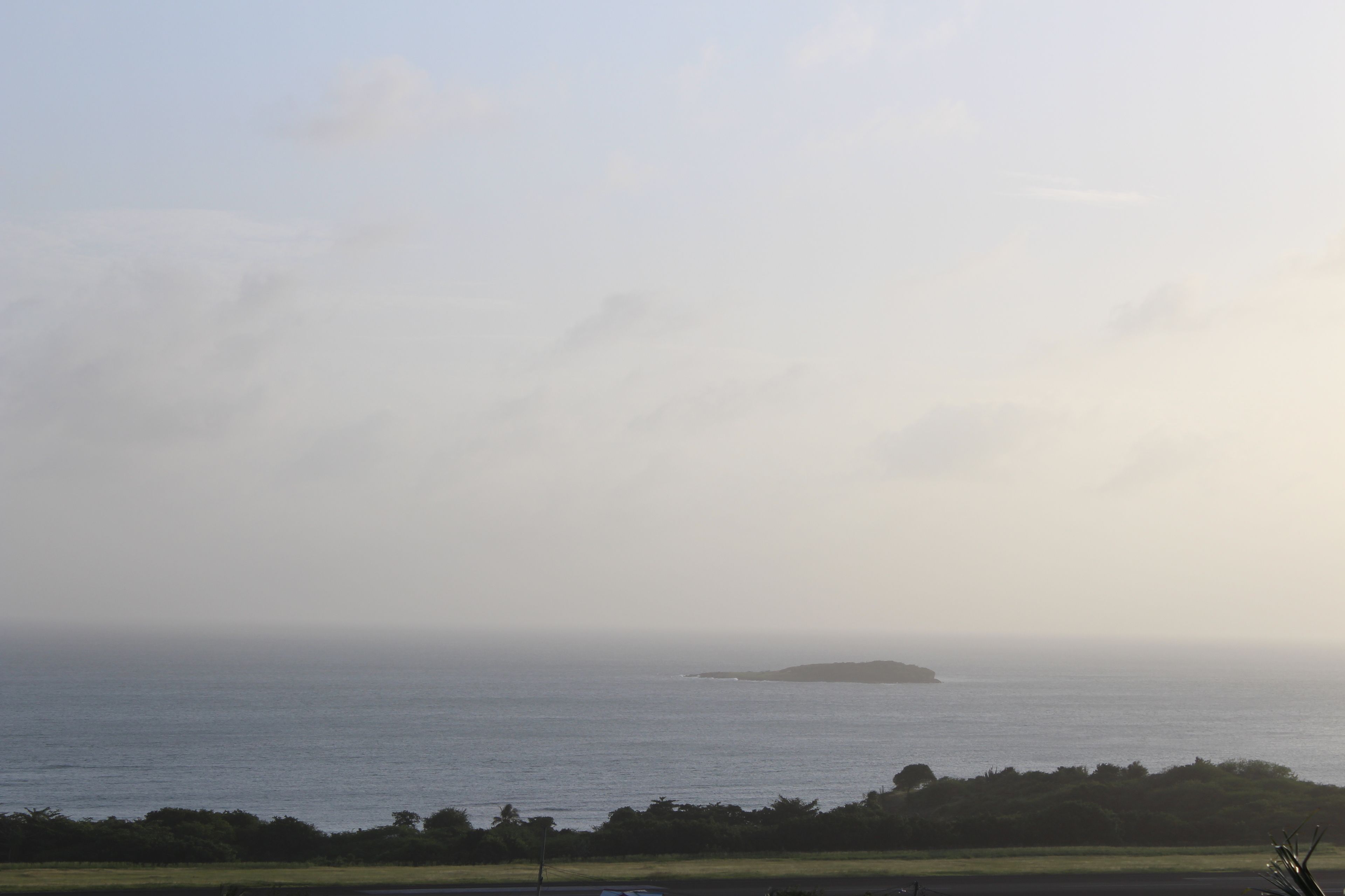 A coastal view with a distant island and a clear sky.