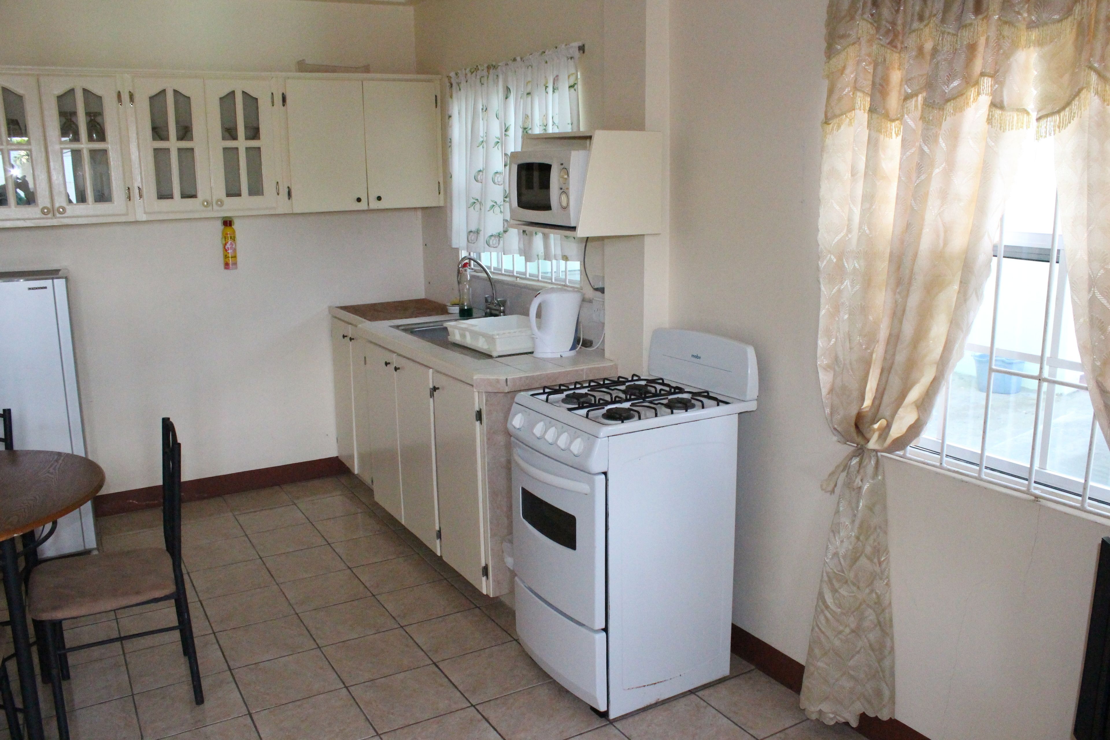 A kitchen with white cabinets, a stove, a microwave, and a sink.