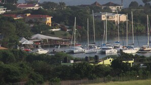 A marina with multiple boats docked, surrounded by residential buildings and lush greenery. - Relax Inn Grenada West Indies (St. George's)