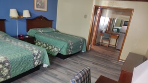 A hotel room with two beds, a desk, a chair, and a mirror.