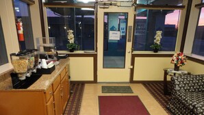 A hotel lobby with a reception desk, a coffee machine, a fire extinguisher, and a sofa.
