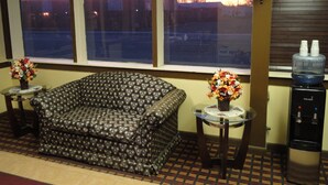 A room with a patterned sofa, a small table with a vase of flowers, and a water dispenser.