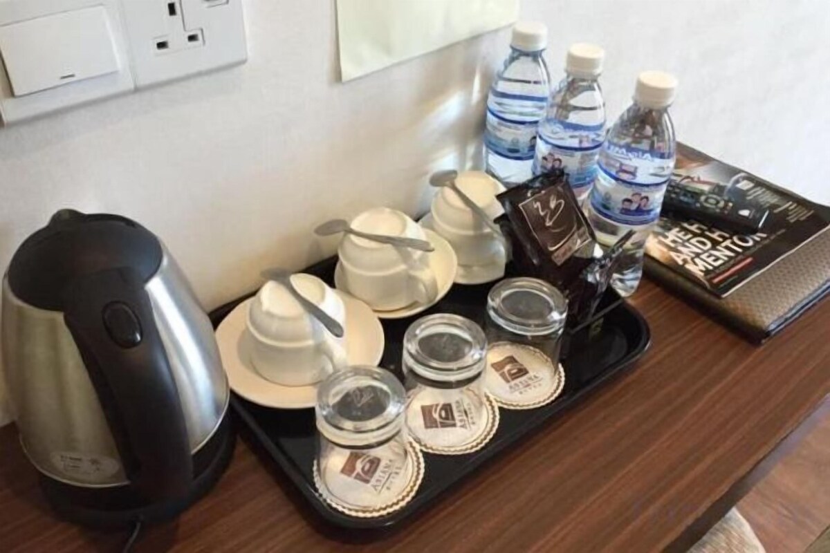 A tray with a coffee maker, tea pots, cups, and water bottles on a wooden surface.