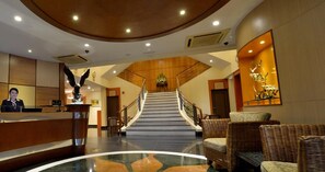 A hotel lobby with a reception desk, a staircase, and wicker furniture. - Asiana Hotel (Kota Kinabalu)