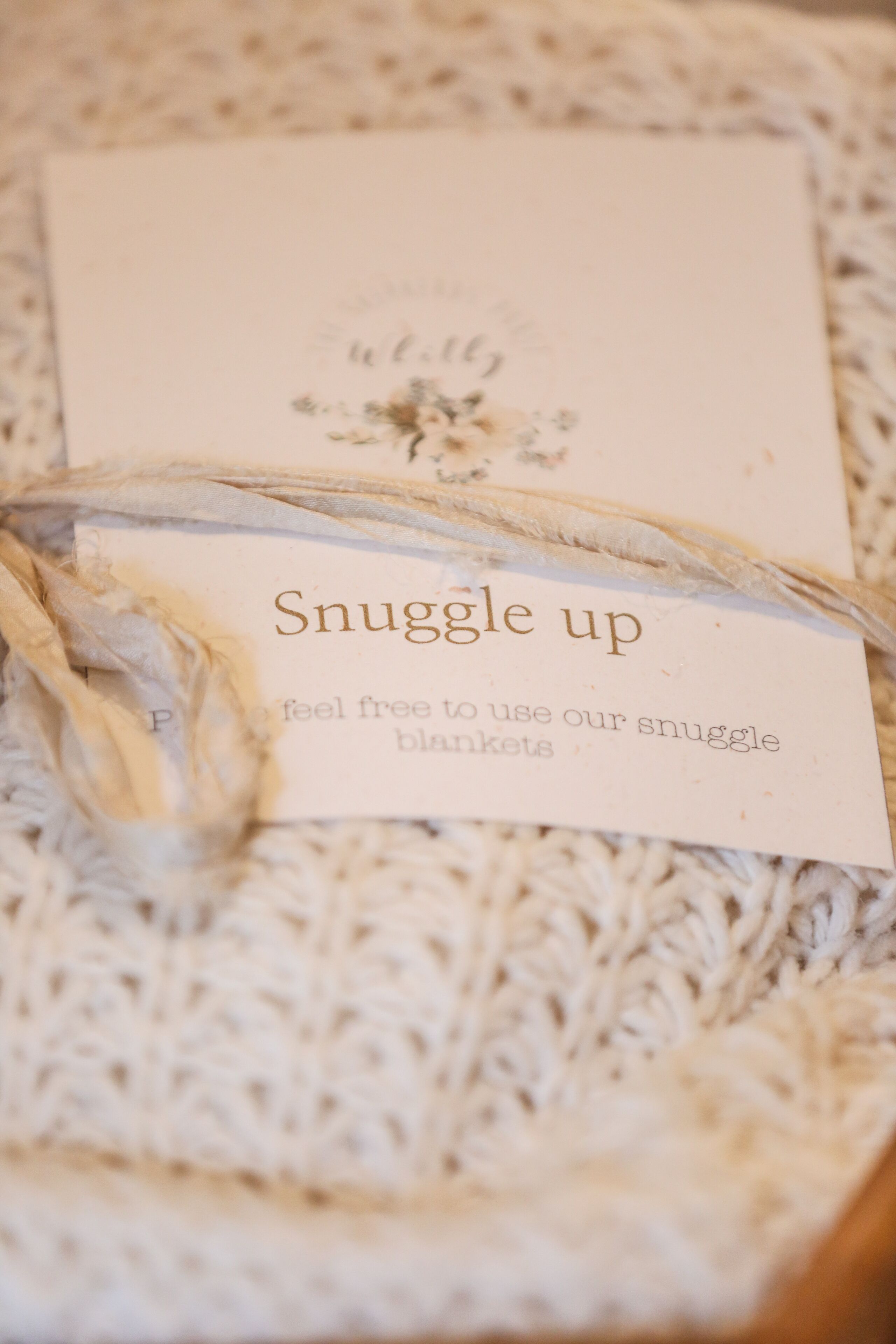 A card with the text "Snuggle up" and "feel free to use our snuggle blankets" on a textured surface.