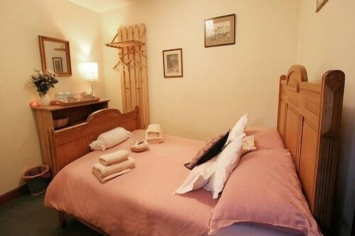 A bedroom with a wooden bed, a bedside table, a lamp, and a wall-mounted towel rack.