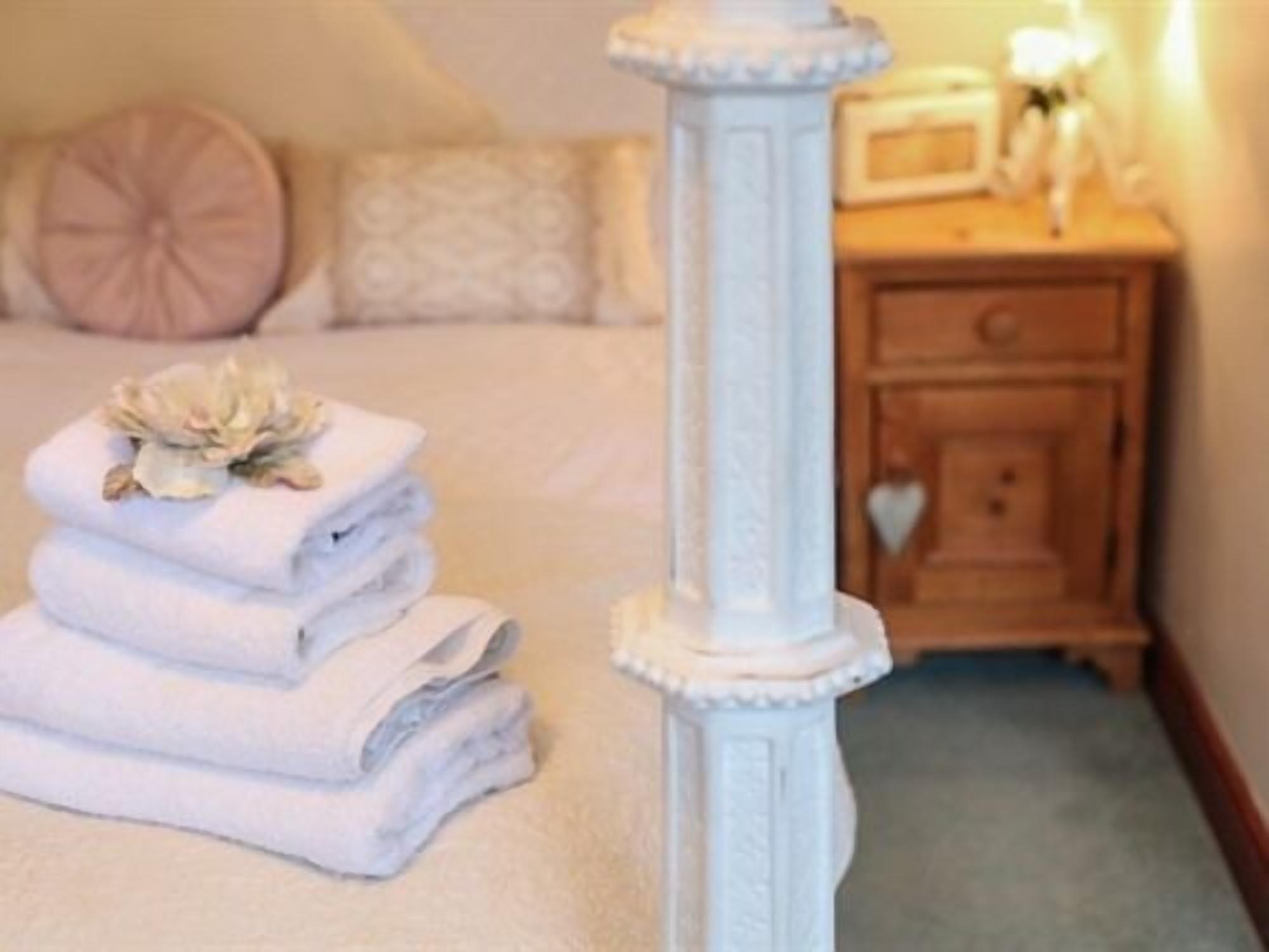 A neatly made bed with folded towels and a decorative pillow.