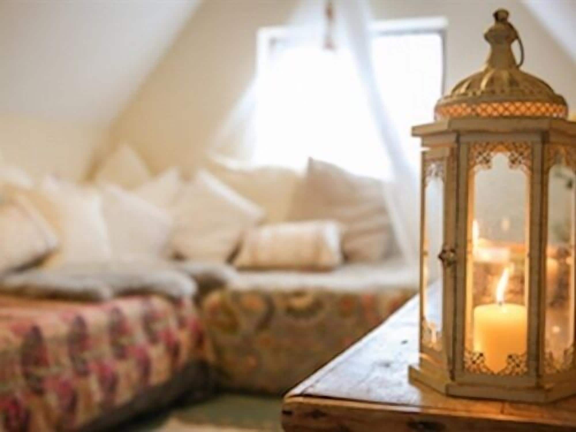 A cozy room with a wooden table, a decorative lantern, and a bed with patterned bedding.