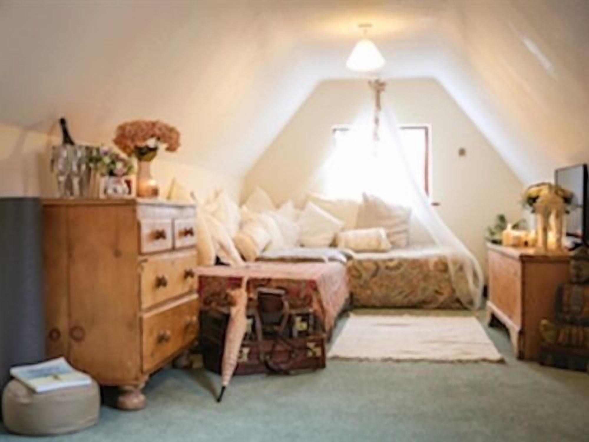 Um quarto de sótão aconchegante, com uma cama, cômoda e um pequeno tapete.