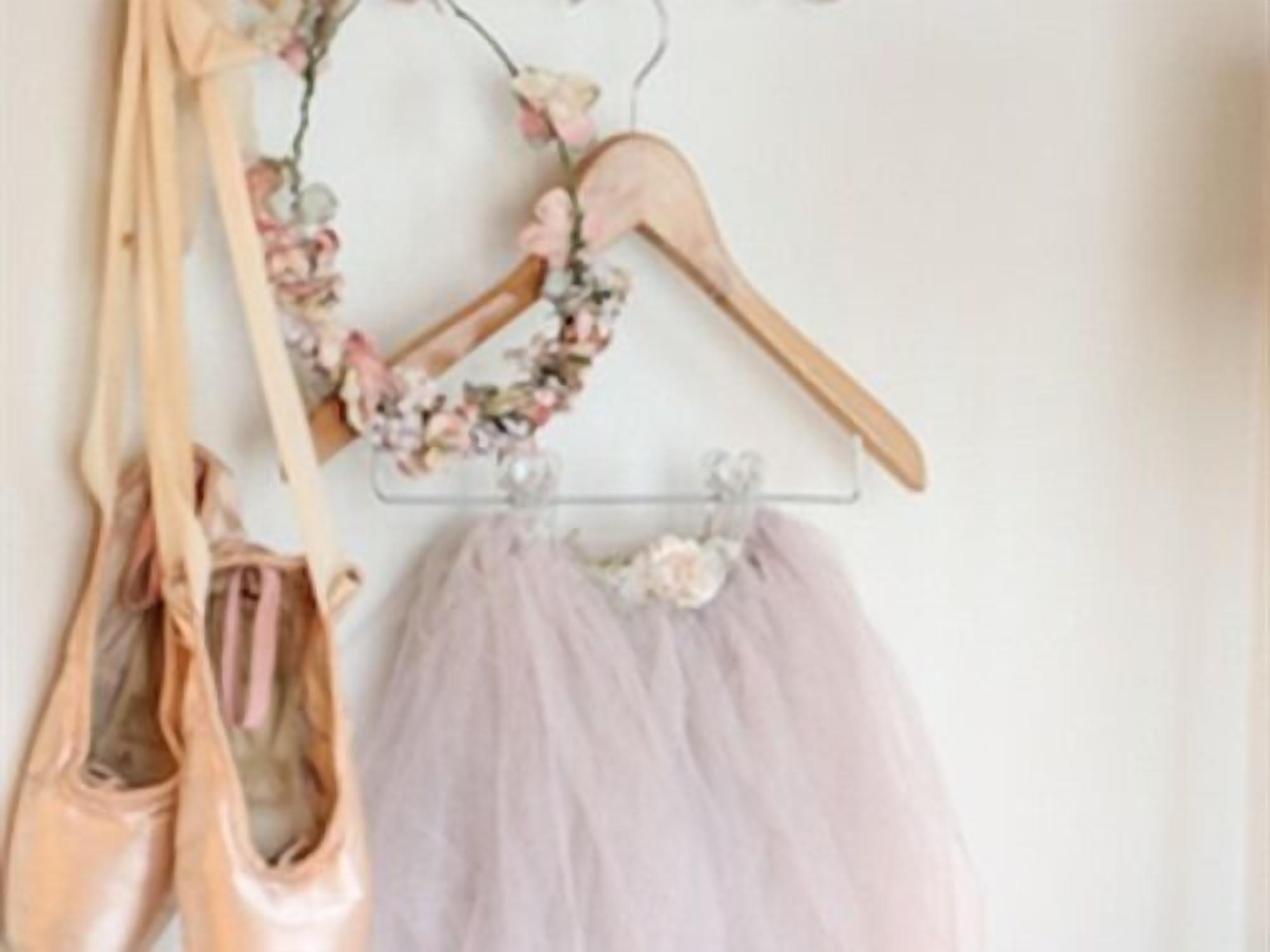 A ballet shoe rack with a tutu and a floral garland.