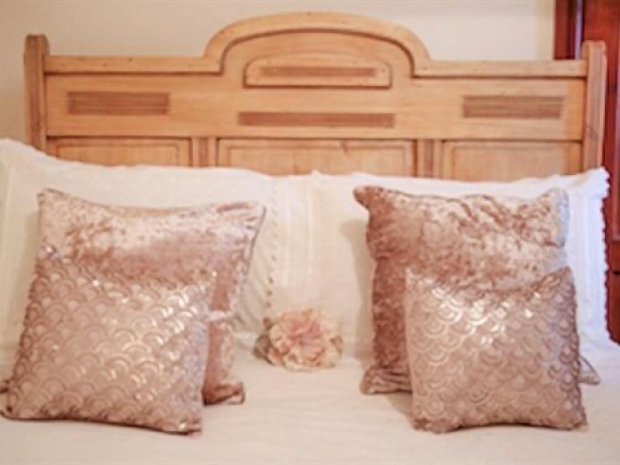 A bed with a wooden headboard and two decorative pillows.