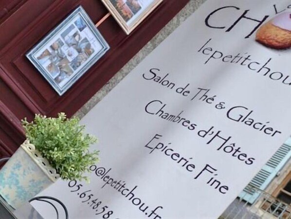 A sign for a hotel named 'CH lepetitchou.fr' with contact information and services listed, including 'Salon de Thé & Glacier', 'Chambres d'Hôtes', and 'Epicerie Fine'.
