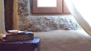 A room with a stone wall, a wooden door, and a window with a view of the sky. - Le Petit Chou (Entraygues-sur-Truyere)