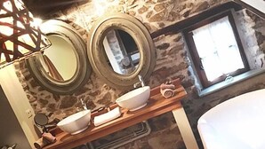 A bathroom with two round mirrors, a wooden vanity with two sinks, and a window. - Le Petit Chou (Entraygues-sur-Truyere)