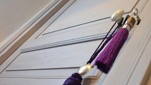 A door with a decorative tassel hanging on a key ring. - Le Petit Chou (Entraygues-sur-Truyere)
