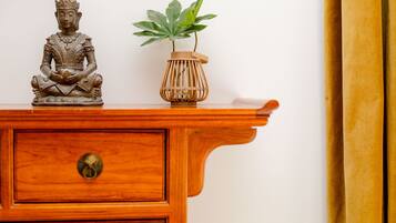 A wooden cabinet with a Buddha statue and a potted plant on top.