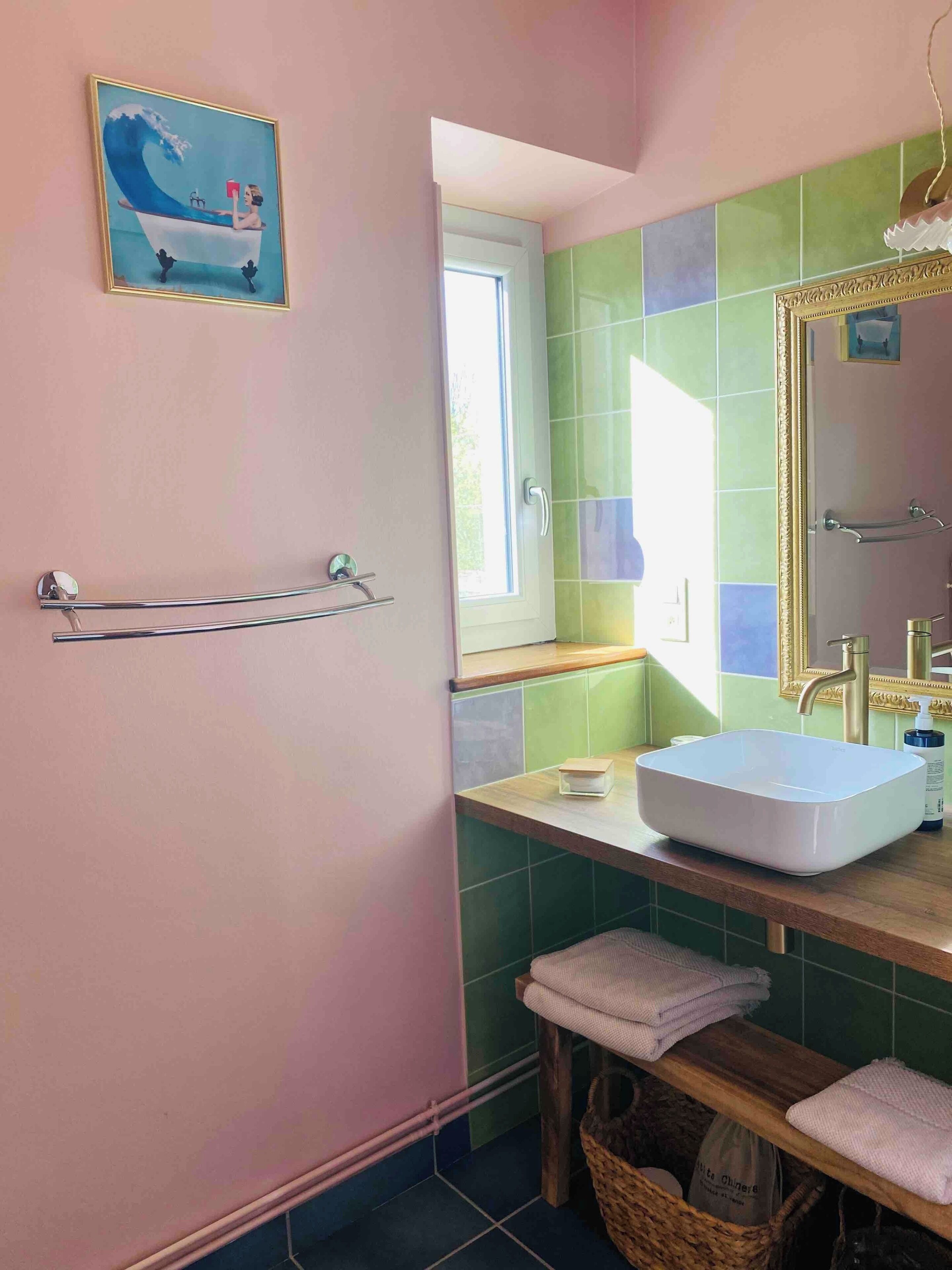 Ein Badezimmer mit großem Fenster, einem Waschbecken, einem Handtuchhalter und einem Spiegel.