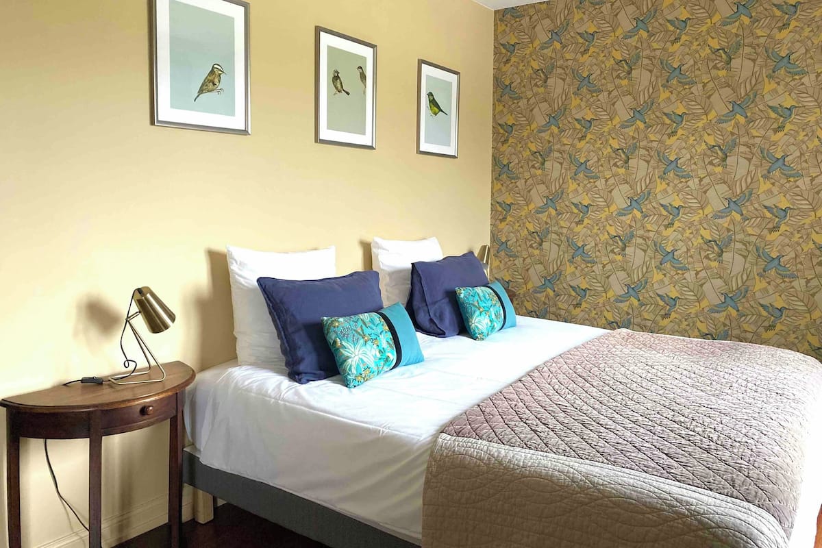 Une chambre d’hôtel avec un lit, une table de chevet et trois tableaux encadrés accrochés au mur.