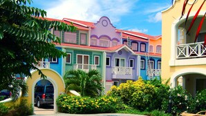 A swimming pool with a lounge chair, surrounded by colorful buildings and lush greenery. - The Harbour (Gros Islet)