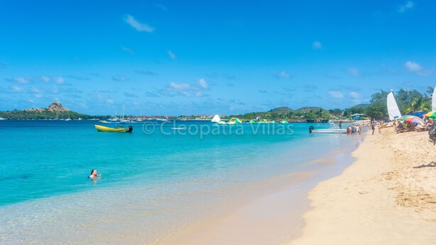 A beach with clear turquoise water, a sandy shore, and boats. - The Harbour (Gros Islet)