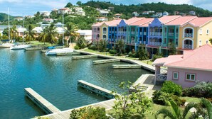 A marina with boats docked, a dock, and colorful buildings with balconies. - The Harbour (Gros Islet)