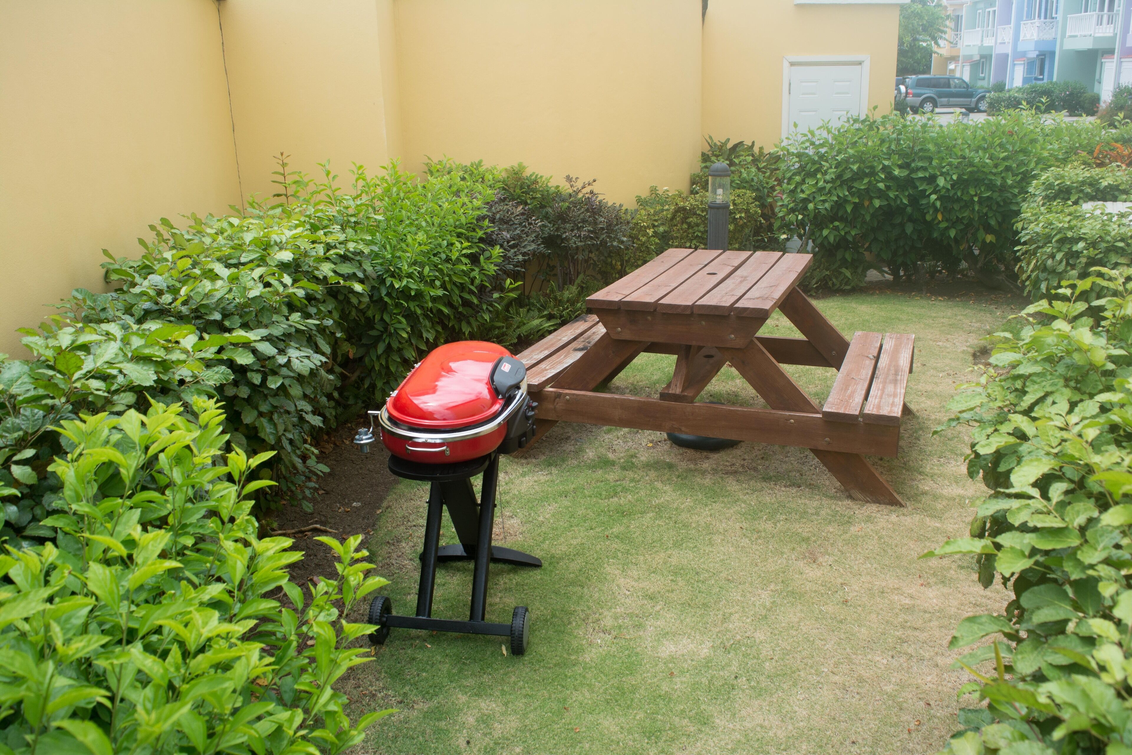 A patio with a wooden table and a barbecue grill.