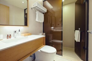 A modern bathroom with a white sink, wooden vanity, a glass shower enclosure, and a toilet. - JI Hotel Dongdan Beijing (Beijing)