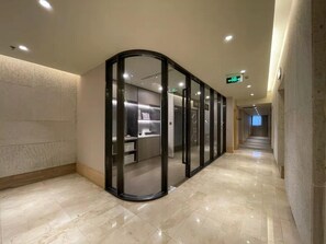 A modern hallway with a curved glass partition leading to a room with shelves and a door. - JI Hotel Dongdan Beijing (Beijing)