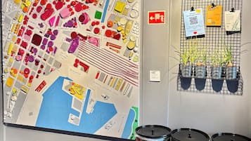 Un mapa gran amb diverses seccions indicades i tres barrils negres etiquetats com a “PLÀSTIC” i “PAPER” a terra.