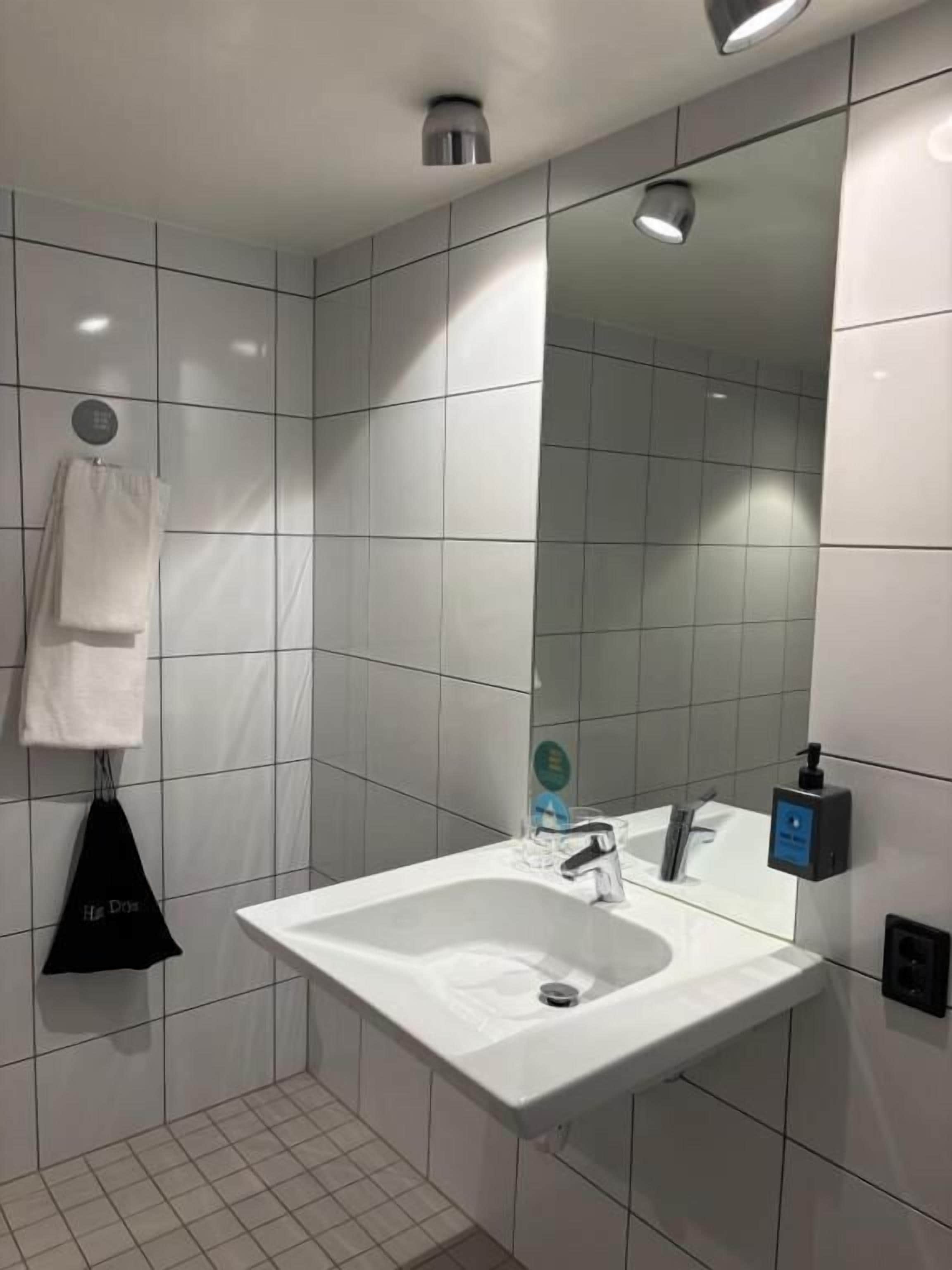 Un bagno moderno con lavandino bianco, specchio e pareti piastrellate.