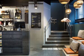 A bar area with a menu board, a staircase, and seating with cushions. - Comfort Hotel Xpress Central Station (Oslo)