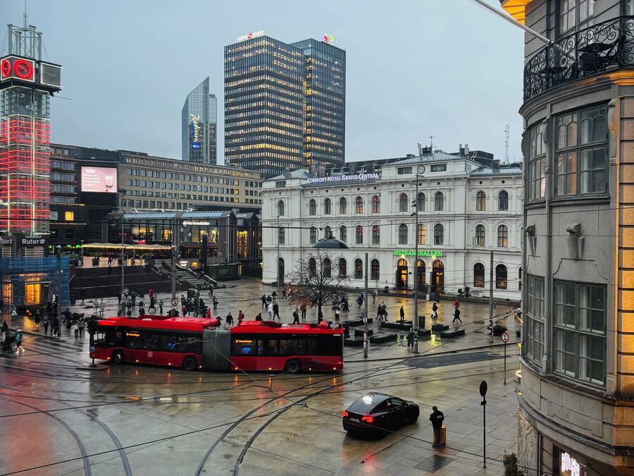 Una plaza de la ciudad con un tranvía, un coche negro y un edificio con un letrero que dice "Comfort Hotel Grand Central".