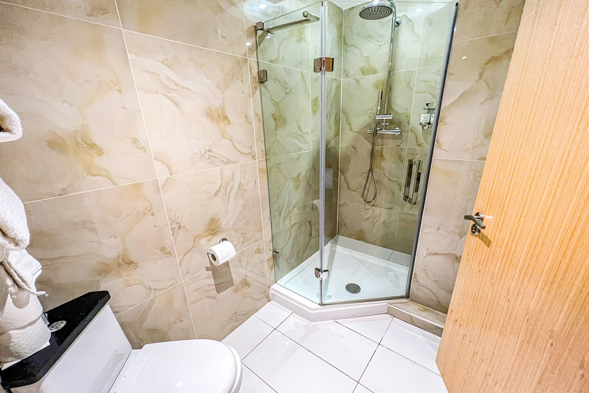 A bathroom with a glass-enclosed shower, a toilet, and a towel rack.