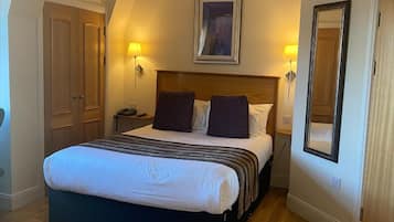 A bedroom with a large bed, two bedside lamps, a framed picture above the bed, and a mirror on the wall.
