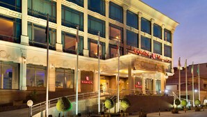 A multi-story hotel with a grand entrance, a staircase, and a sign reading "RAMADA." - Ramada by Wyndham Riyadh (Riyadh)