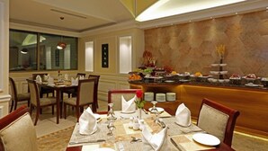 A dining area with a buffet setup, a separate dining table, and a decorative wall. - Ramada by Wyndham Riyadh (Riyadh)